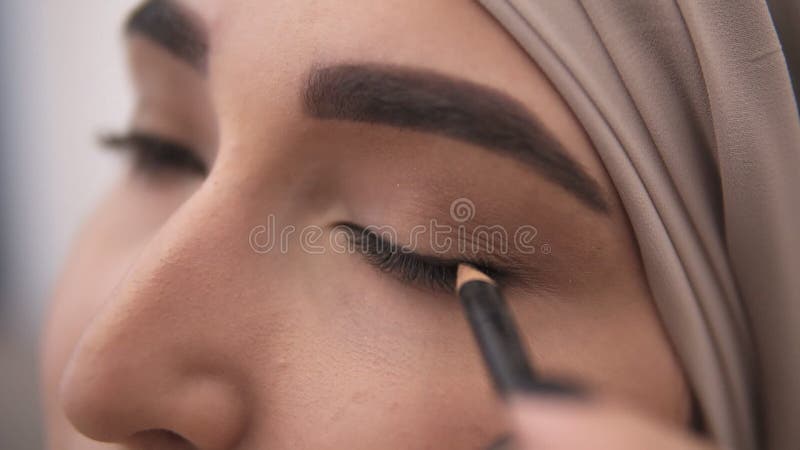 Extrêmement étroit vers le haut de la vue d'une jeune femme musulmane faisant une flèche sur sa paupière utilisant l'eyepencil no clips vidéos