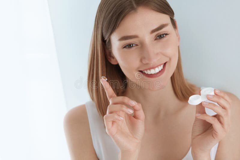 Eye lens. Smiling woman with contact eye lenses and container