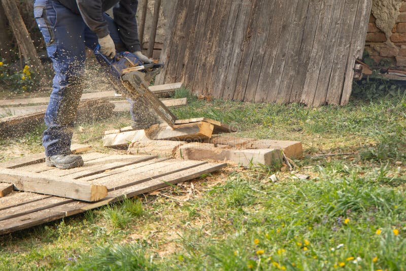 Eye-level shot of a person sawing pieces of wood with an electric saw in the garden. An eye-level shot of a person sawing pieces of wood with an electric saw in royalty free stock images Eye-level shot of a person sawing pieces of wood with an electric saw in the garden. An eye-level shot of a person sawing pieces of wood with an electric saw in royalty free stock images