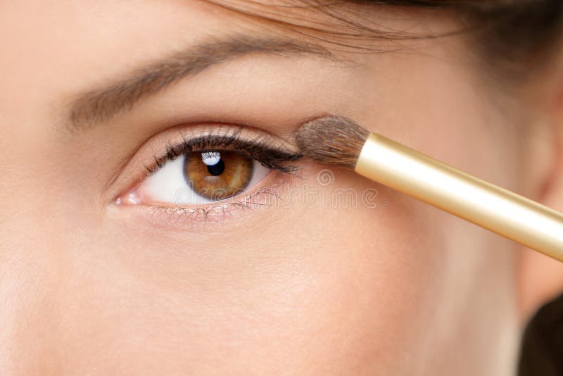 Eye makeup woman applying eyeshadow powder. Woman putting shadow powder on eyes with makeup brush. Closeup of eyelid and eyebrow.