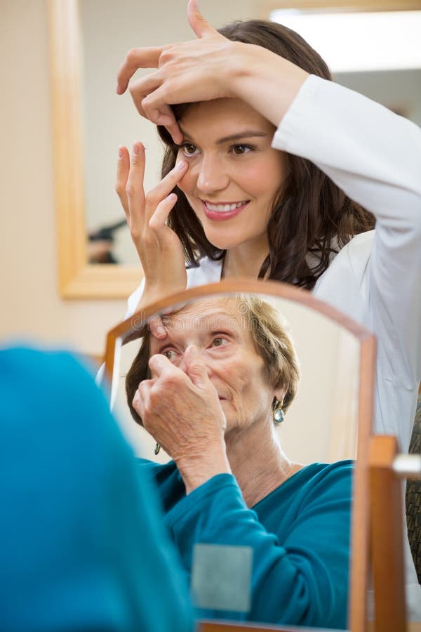 Eyecare Doctor Teaching Senior Woman To Insert royalty free stock photo Eyecare Doctor Teaching Senior Woman To Insert royalty free stock photo
