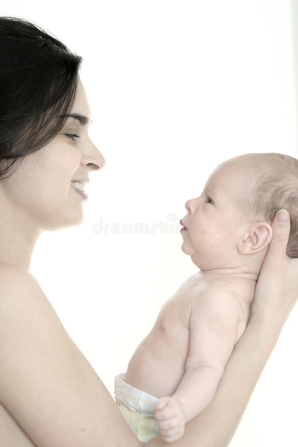 Mother and her one month old son are together and looking to each other. The mother holds his baby in her arm. This is high-key photo in front of a white background. Mother and her one month old son are together and looking to each other. The mother holds his baby in her arm. This is high-key photo in front of a white background.