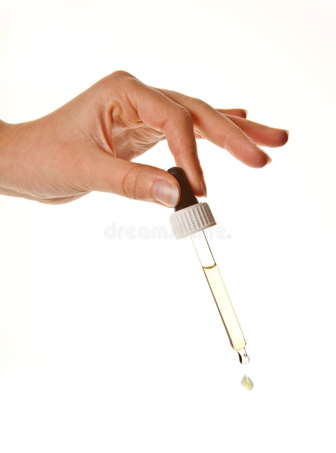 Hands of a woman holding an eyerdropper with fluid. Hands of a woman holding an eyerdropper with fluid