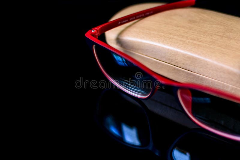 Eyeglass with Wooden Case on Top of Reflective Surface Editorial Photo