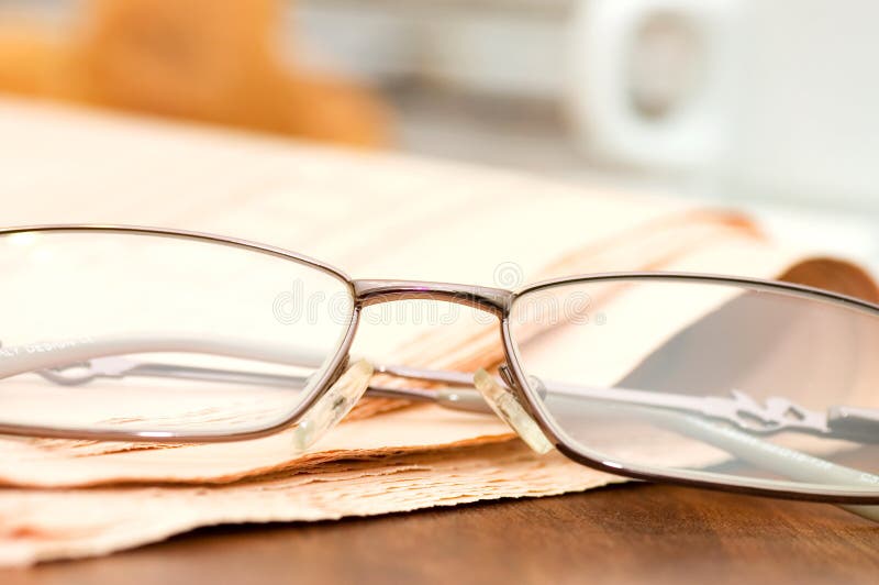 Eyeglasses no jornal em uma tabela de madeira foto de stock royalty free Eyeglasses no jornal em uma tabela de madeira foto de stock royalty free