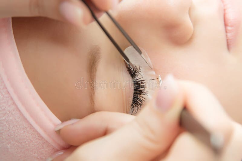 Eyelash Extension Procedure. Woman Eye with Long Eyelashes.