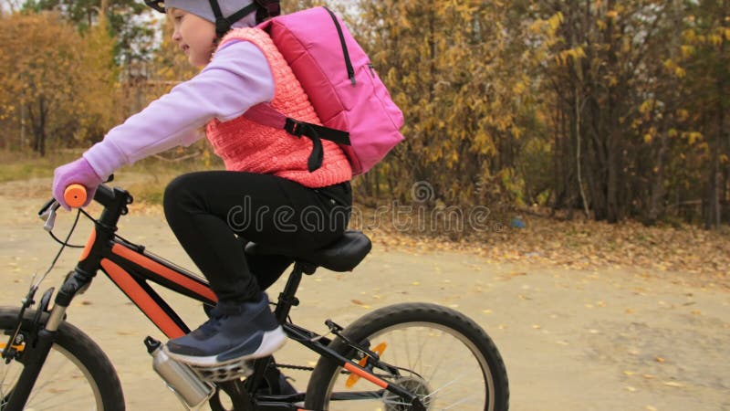 Eén kaukasische kinderfietsweg in het herfstpark Klein meisje met zwarte oranje cyclus in het bos Kid doet het wel