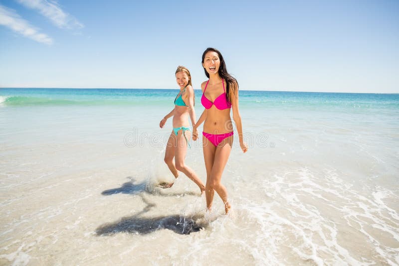 Żeńscy przyjaciele trzyma ręki na plaży obrazy stock