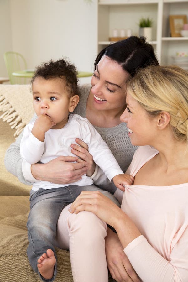 Same sex femal couple sitting with their son at home. Same sex femal couple sitting with their son at home