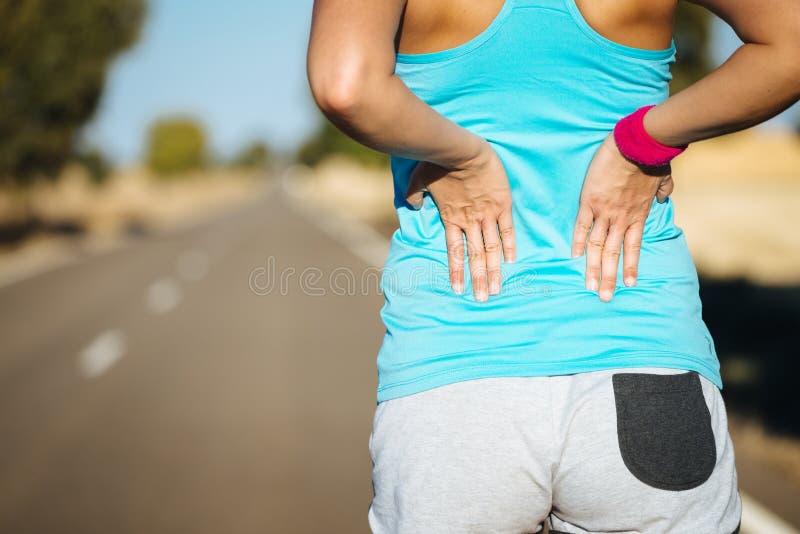 Female runner athlete back injury and pain. Woman suffering from painful lumbago or kidney illness while running in rural road. Female runner athlete back injury and pain. Woman suffering from painful lumbago or kidney illness while running in rural road.