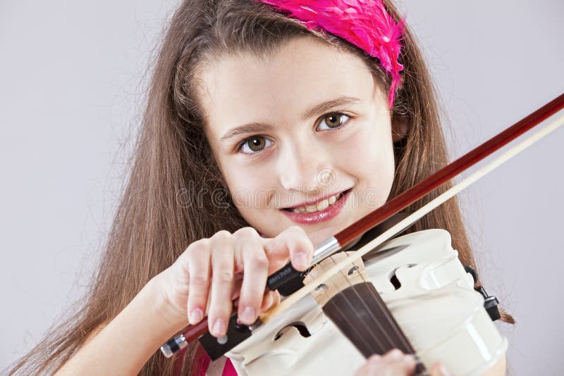 Female child playing the violin with gray background. Female child playing the violin with gray background