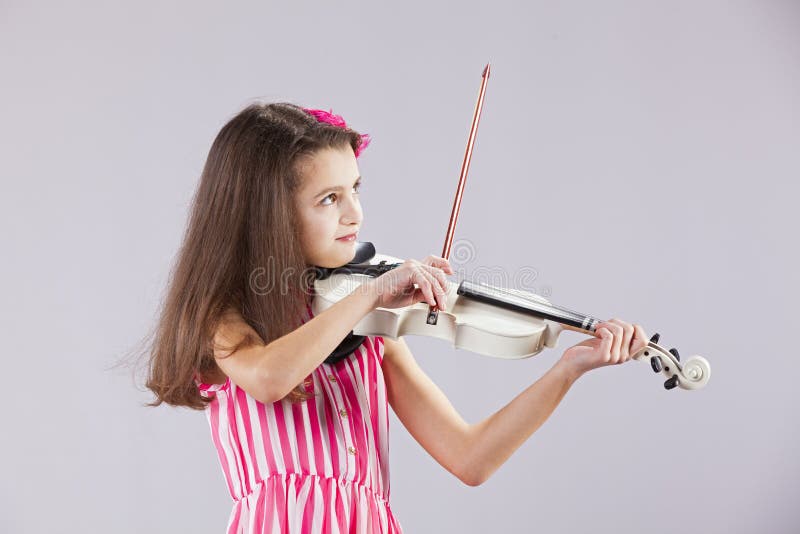 Female child playing the violin with gray background. Female child playing the violin with gray background