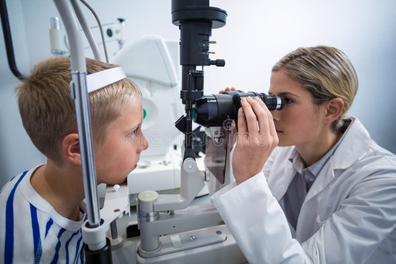 Żeński optometrist egzamininuje młodego pacjenta na rozchylenie lampie obrazy royalty free Żeński optometrist egzamininuje młodego pacjenta na rozchylenie lampie obrazy royalty free