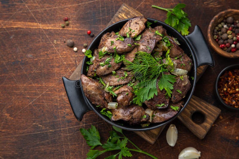 Fígado de frango frito com cebola e ervas fundo preto vista superior