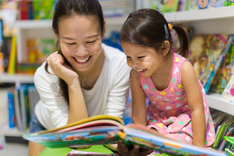 Mother and her young daughter 
enjoying a picture book together in a bookstore. Mother and her young daughter 
enjoying a picture book together in a bookstore.