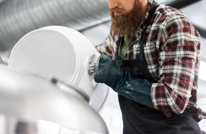 Fabbricante di birra che lavora nella fabbrica di birra del mestiere o nella pianta della birra fotografia stock Fabbricante di birra che lavora nella fabbrica di birra del mestiere o nella pianta della birra fotografia stock