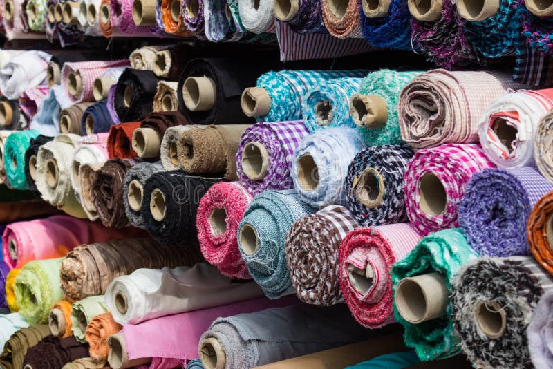 Fabric rolls at market stall , textile industry background