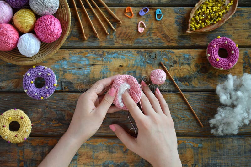 Making crochet amigurumi donuts. Toy for babies or trinket.  On the table threads, needles, hook, cotton yarn. Handmade gift. DIY crafts concept. Step 2. Stuff the toy with padding polyester. Making crochet amigurumi donuts. Toy for babies or trinket.  On the table threads, needles, hook, cotton yarn. Handmade gift. DIY crafts concept. Step 2. Stuff the toy with padding polyester