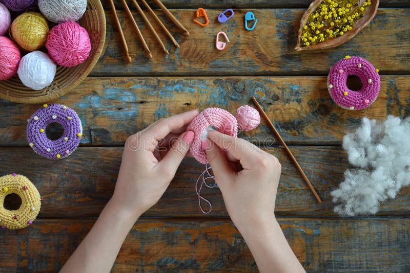 Making crochet amigurumi donuts. The toy for babies or trinket. On the table threads, needles, hook, cotton yarn. Handmade gift. DIY crafts concept. Step 2. Stuff the toy with padding polyester. Making crochet amigurumi donuts. The toy for babies or trinket. On the table threads, needles, hook, cotton yarn. Handmade gift. DIY crafts concept. Step 2. Stuff the toy with padding polyester