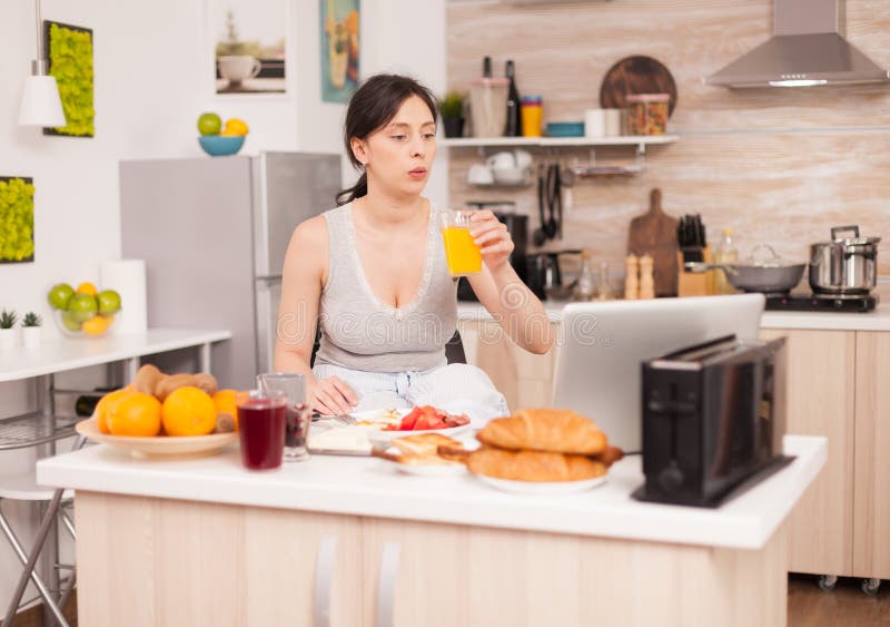 Woman making online shopping in the morning during breakfast paying with credit card. Entering information, customer using e-commerce technology buying stuff on the web, cosumerism banking and ordering. Woman making online shopping in the morning during breakfast paying with credit card. Entering information, customer using e-commerce technology buying stuff on the web, cosumerism banking and ordering