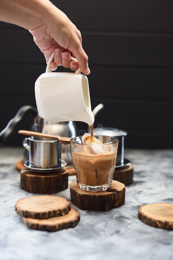Fabrication du café glacé avec le style vietnamien de lait de noix de coco Café se renversant de main de femme sur la glace sur l photographie stock libre de droits Fabrication du café glacé avec le style vietnamien de lait de noix de coco Café se renversant de main de femme sur la glace sur l photographie stock libre de droits