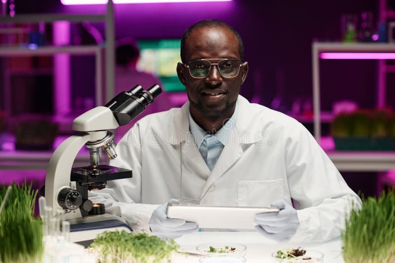 Fabrikforscher, der an seinem Schreibtisch im Labor sitzt und sich die Kamera anschaut stockfoto