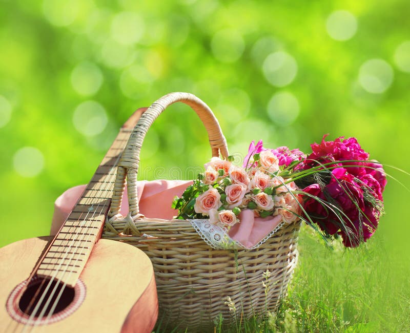 Fabulera, älska, begreppet för dagen för valentin` s - vide- korg med buketten av blommor, gitarr på gräset royaltyfria bilder Fabulera, älska, begreppet för dagen för valentin` s - vide- korg med buketten av blommor, gitarr på gräset royaltyfria bilder