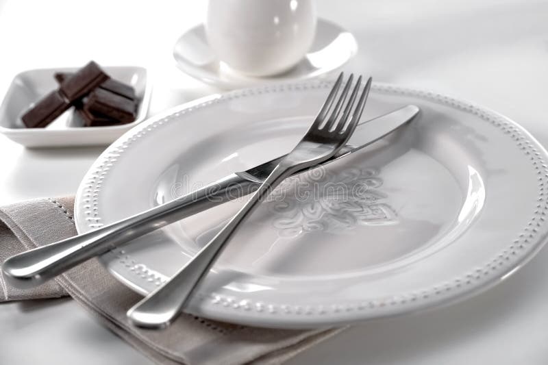Faca e forquilha do ajuste da tabela na placa da porcelana, no pano de linho, na bacia de partes do chocolate e no copo com os pi fotos de stock Faca e forquilha do ajuste da tabela na placa da porcelana, no pano de linho, na bacia de partes do chocolate e no copo com os pi fotos de stock