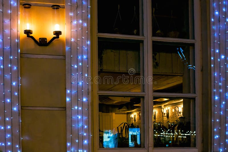 Facade of a cafe with a large wooden window with a street lamp.