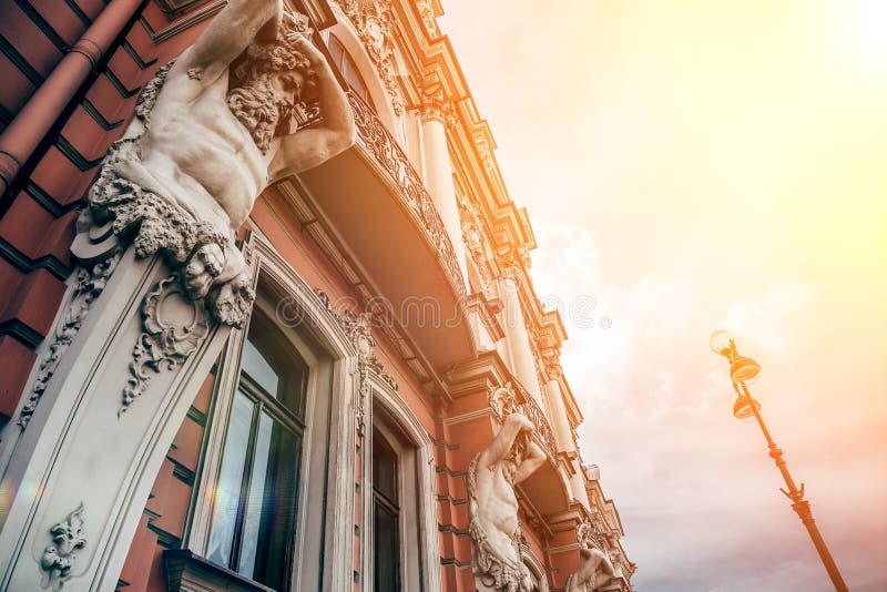 Facade of old building in St. Petersburg with statues of titans in sunshine