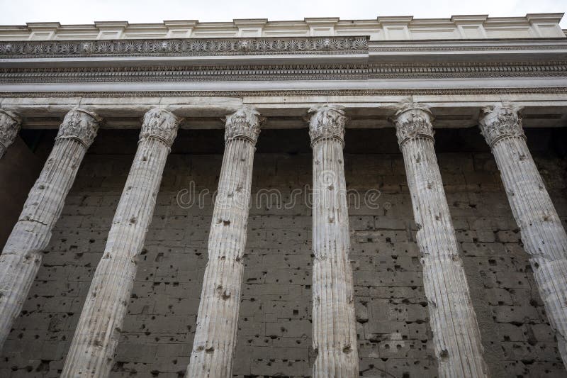 The facade of the Temple di Adriano in Rome, Italy. Perspective of ancient colonnade in the foreground