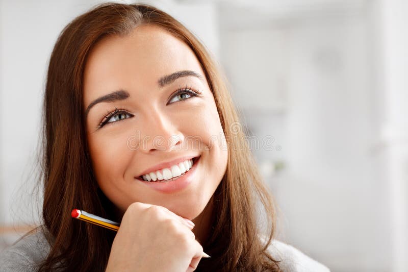 Faccia a donna e matita che pensano con sorriso e ispirazione per scrivere educazione e conoscenza a casa. intuizione fotografia stock