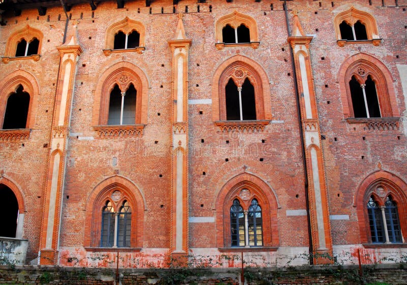 Facciata rossa con nove finestre munite di montanti meravigliose nel castello di Vigevano vicino a Pavia in Lombardia (Italia) fotografia stock libera da diritti Facciata rossa con nove finestre munite di montanti meravigliose nel castello di Vigevano vicino a Pavia in Lombardia (Italia) fotografia stock libera da diritti