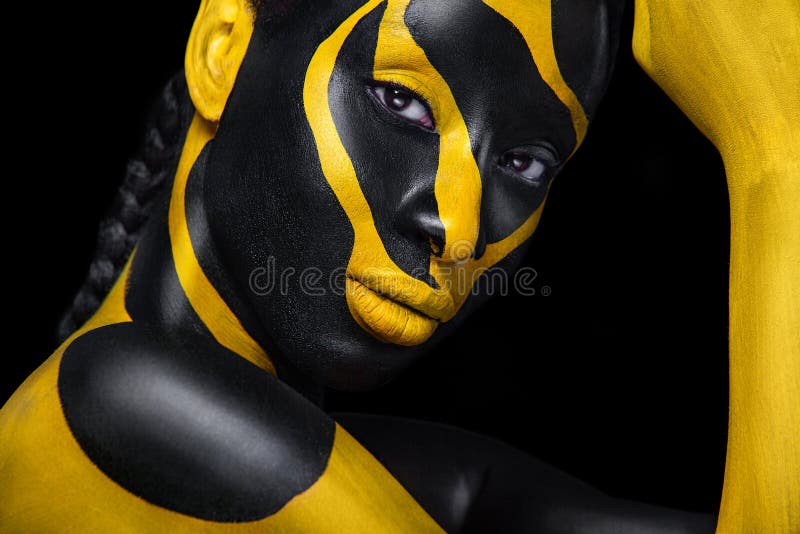 Yellow and black body paint. Woman with face art. Young girl with