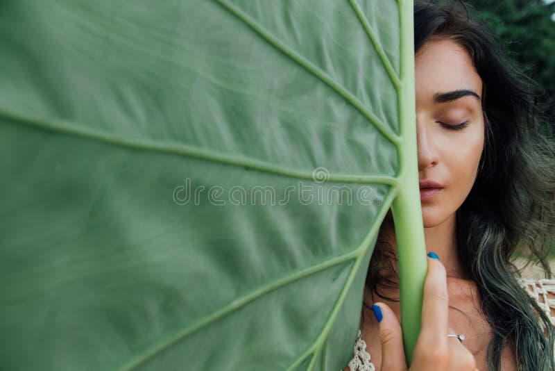 Face attractive young woman against a large green leaf tropical tree