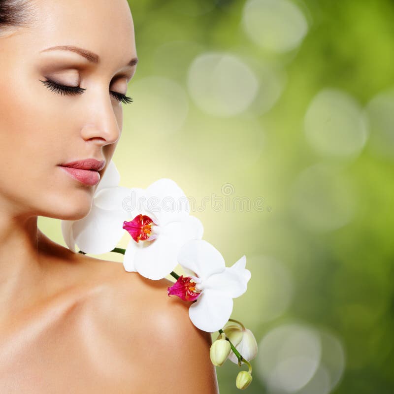 Face of beautiful woman with a white orchid flower royalty free stock photography