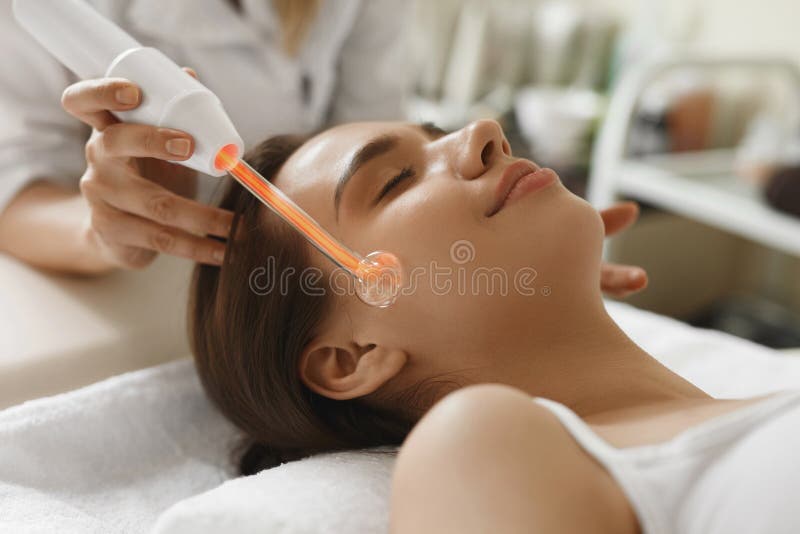 Face Beauty Treatment. Woman Using Darsonval Skin Care Device