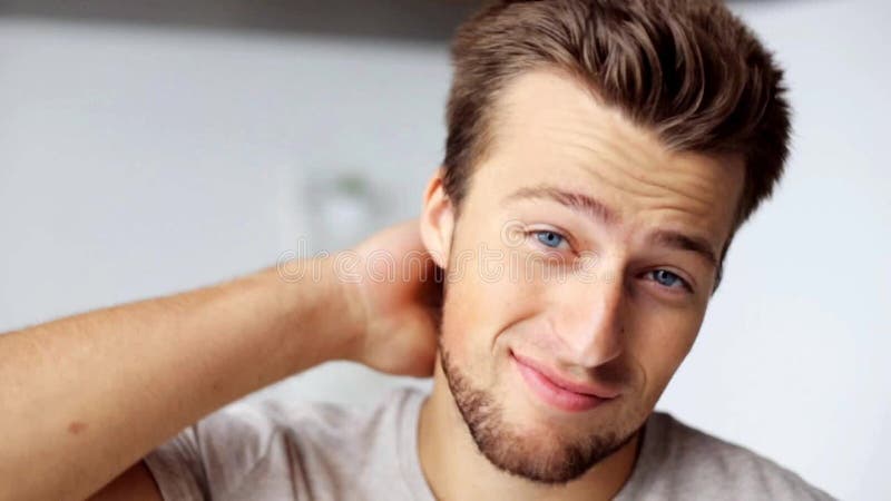 Face of happy smiling young man touching hair