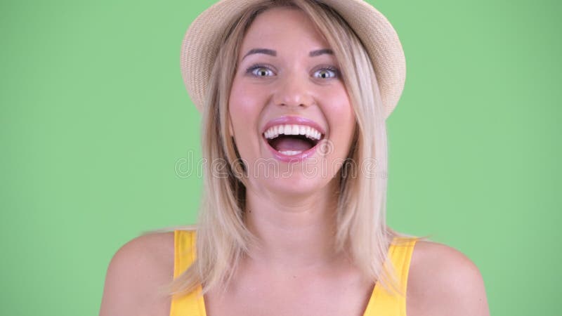 Face of happy young blonde tourist woman looking surprised