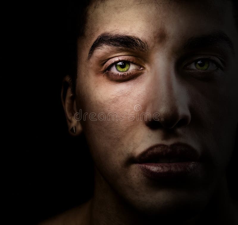 Face of man in the dark with beautiful green eyes