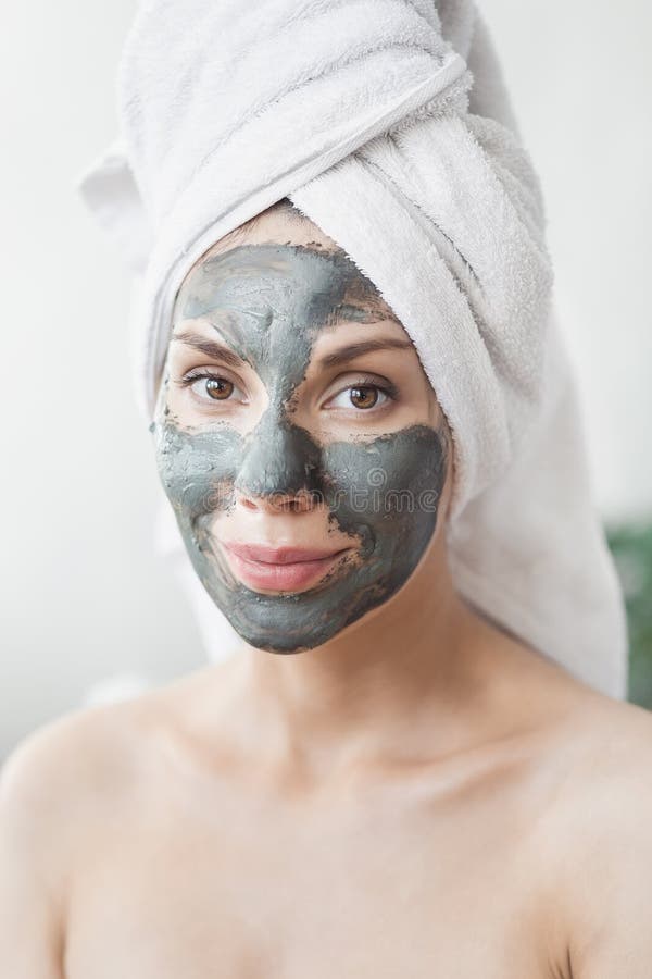 Face Skin care. Attractive Young Woman Wrapped in Bath Towel, applying clay mud mask to face. Skin care concept. Girl royalty free stock image Face Skin care. Attractive Young Woman Wrapped in Bath Towel, applying clay mud mask to face. Skin care concept. Girl royalty free stock image