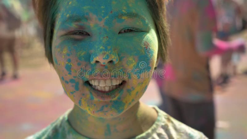 Face of young happy asian girl is smiling with colourful powder on holi festival in daytime in summer, color concept