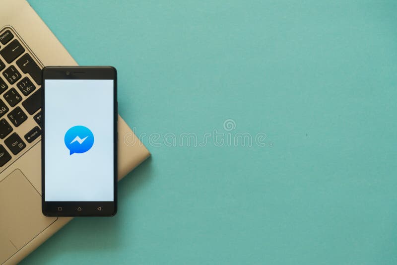 Facebook messenger logo on smartphone placed on laptop keyboard.