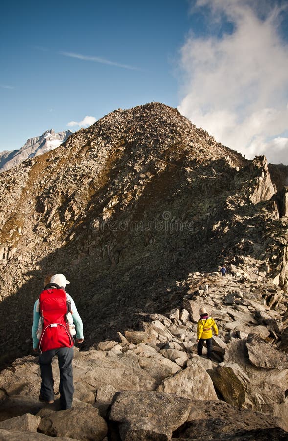 Mother with childcarrier with baby hiking on eggishorn. Mother with childcarrier with baby hiking on eggishorn