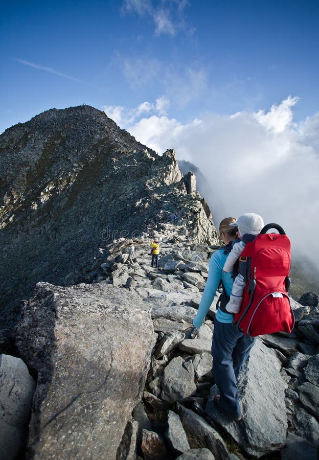 Mother with childcarrier with baby hiking on eggishorn. Mother with childcarrier with baby hiking on eggishorn