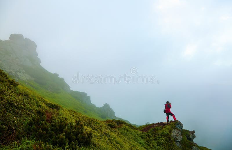 Facet z fotografii kamerą zostaje na crag w mgle obraz stock Facet z fotografii kamerą zostaje na crag w mgle obraz stock