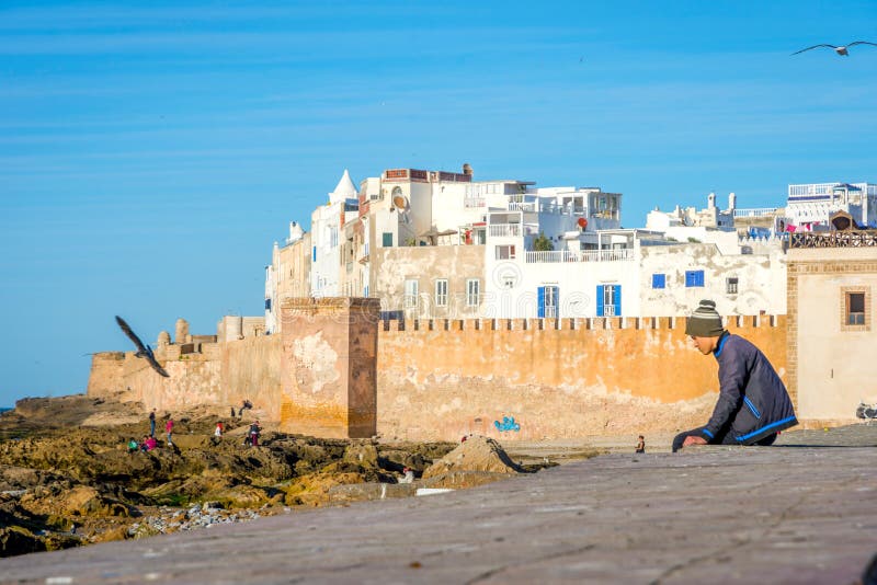 Faceta obsiadanie na miasto ścianie, Essaouira fotografia royalty free Faceta obsiadanie na miasto ścianie, Essaouira fotografia royalty free