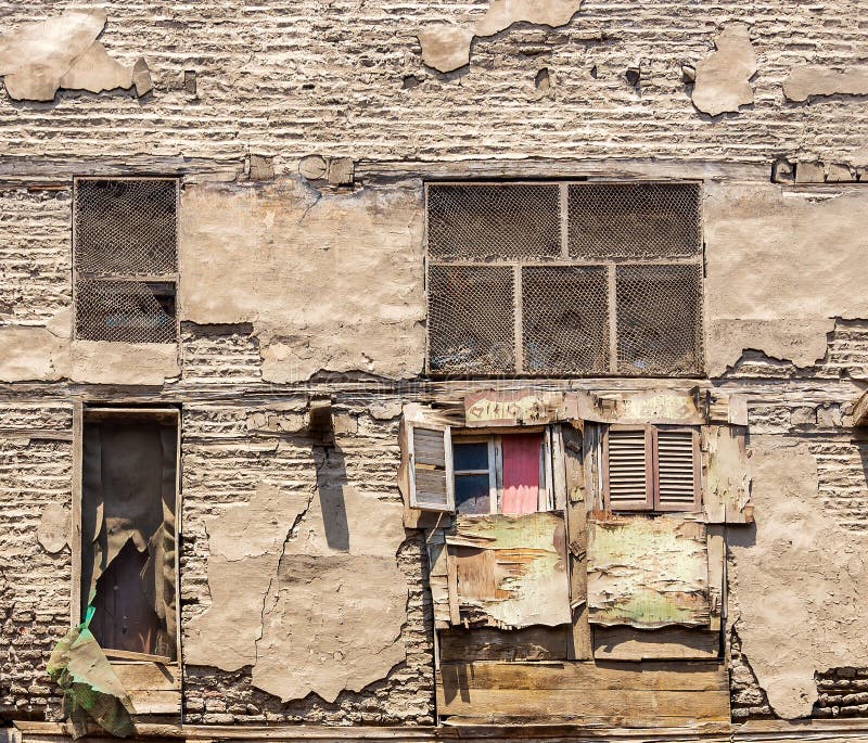 Fachada de un edificio abandonado viejo con la pared de ladrillos de piedra del grunge y las ventanas de madera dispersadas con l foto de archivo Fachada de un edificio abandonado viejo con la pared de ladrillos de piedra del grunge y las ventanas de madera dispersadas con l foto de archivo