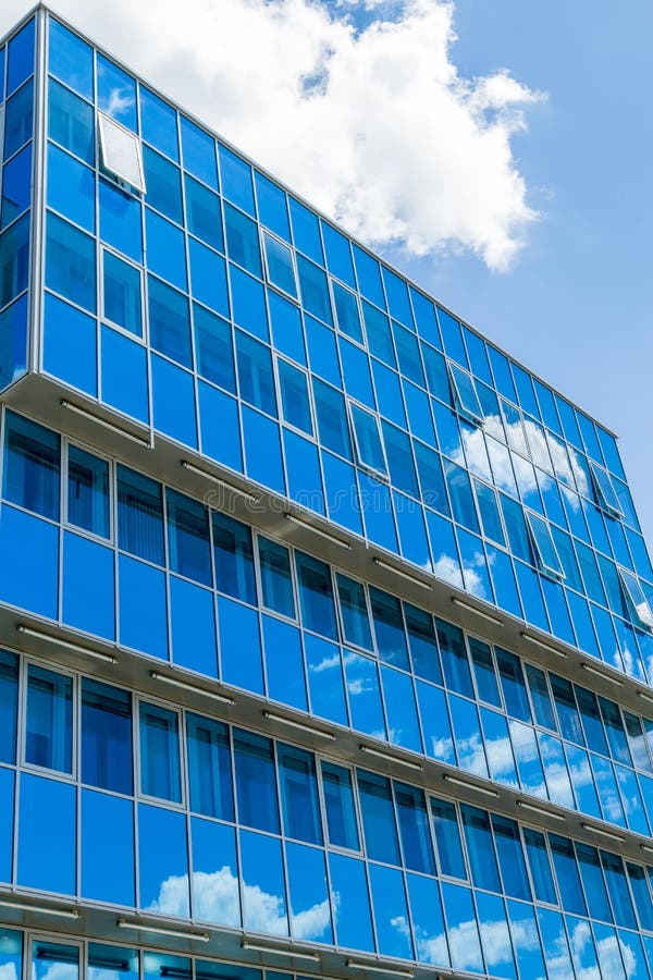 Fachada de un edificio moderno Windows de cristal reflejó el cielo y las nubes gamma azul imagen de archivo libre de regalías Fachada de un edificio moderno Windows de cristal reflejó el cielo y las nubes gamma azul imagen de archivo libre de regalías