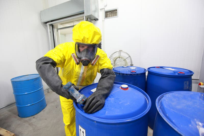 Fully protected in yellow uniform,mask,and gloves professional filling barrel with chemicals. Fully protected in yellow uniform,mask,and gloves professional filling barrel with chemicals